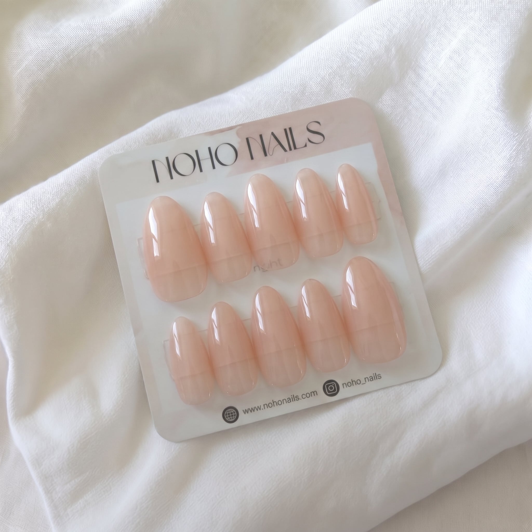 Be Still press-on nails by Noho Nails: ten long almond nails in sheer peachy nude jelly on a Noho Nails display card