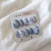 Chinoiserie press-on nails by Noho Nails: blue and white porcelain floral nails and blue cat-eye nails on a Noho Nails display card