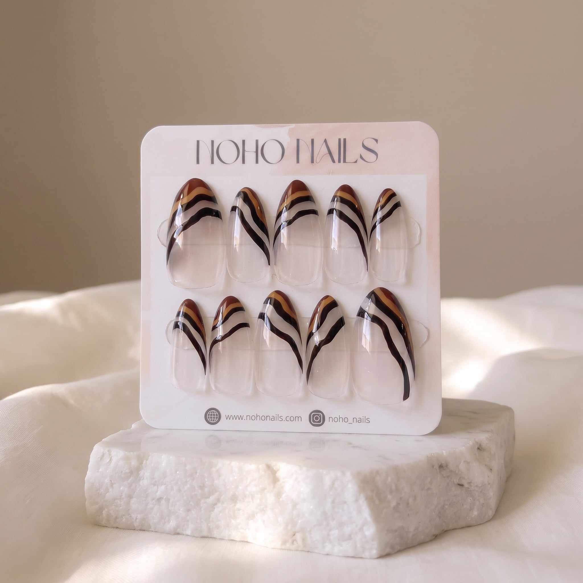 Ombre Portée press-on nails on a Noho Nails display card standing on a white stone block