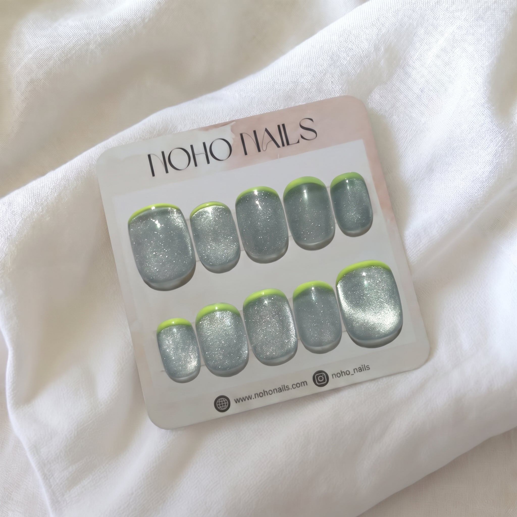 Limelight press-on nails by Noho Nails: short silver cat-eye nails with neon lime French tips on a Noho Nails display card