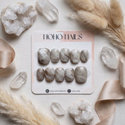 Sediment No. 9 press-on nails on a Noho Nails display card surrounded by quartz crystals, dried pampas grass and champagne satin ribbon