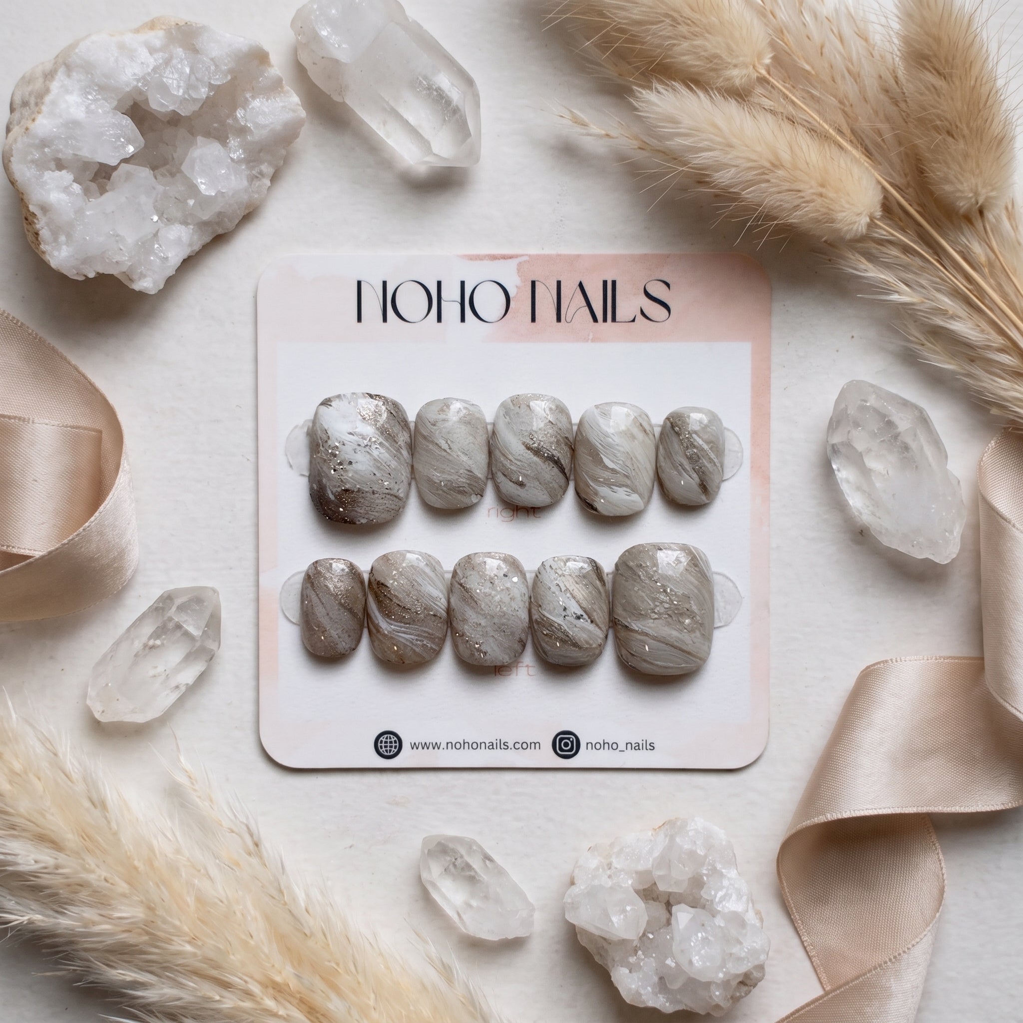 Sediment No. 9 press-on nails on a Noho Nails display card surrounded by quartz crystals, dried pampas grass and champagne satin ribbon