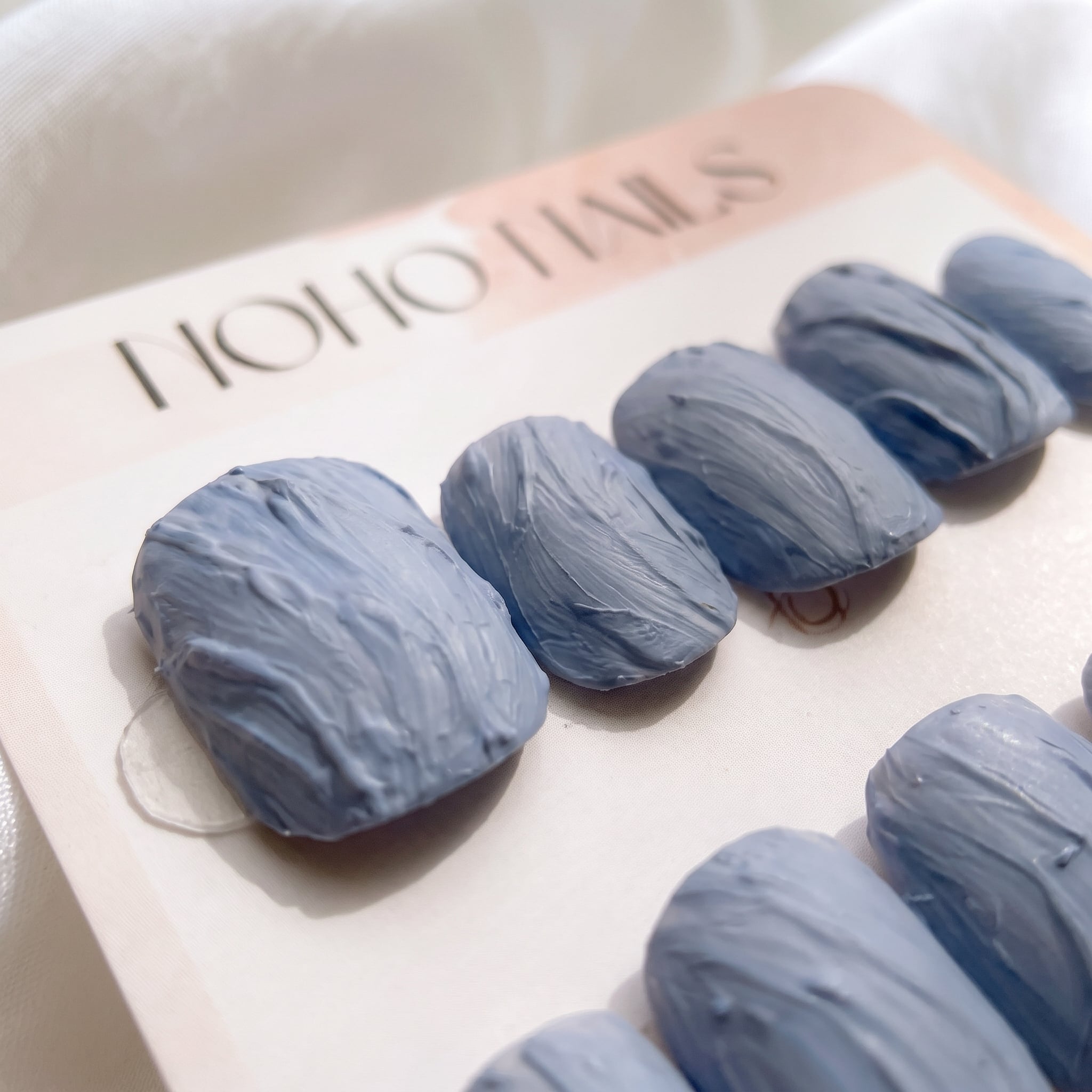 Close-up of Slate Relief press-on nails by Noho Nails: dusty blue-gray nails with a raised hand-sculpted texture