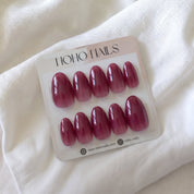 Vino press-on nails by Noho Nails: ten short almond nails in sheer berry wine jelly on a Noho Nails display card