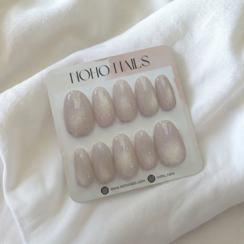 Prosecco Pearl press-on nails by Noho Nails: ten blush-pink nails with champagne cat-eye shimmer and a glossy finish on a display card