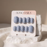 Slate Relief press-on nails on a Noho Nails display card standing on a white stone block