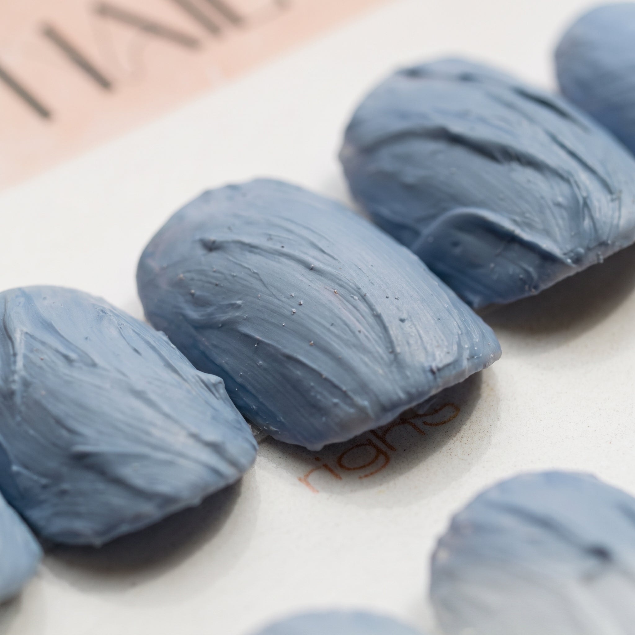Macro close-up of Slate Relief press-on nails by Noho Nails showing the hand-sculpted ridges and swept grooves in matte dusty blue-gray
