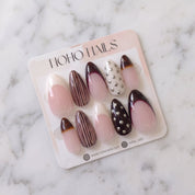Noir et Crème press-on nails on a Noho Nails display card lying on white marble