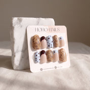 Petite Tache press-on nails on a Noho Nails display card propped against a white marble stone