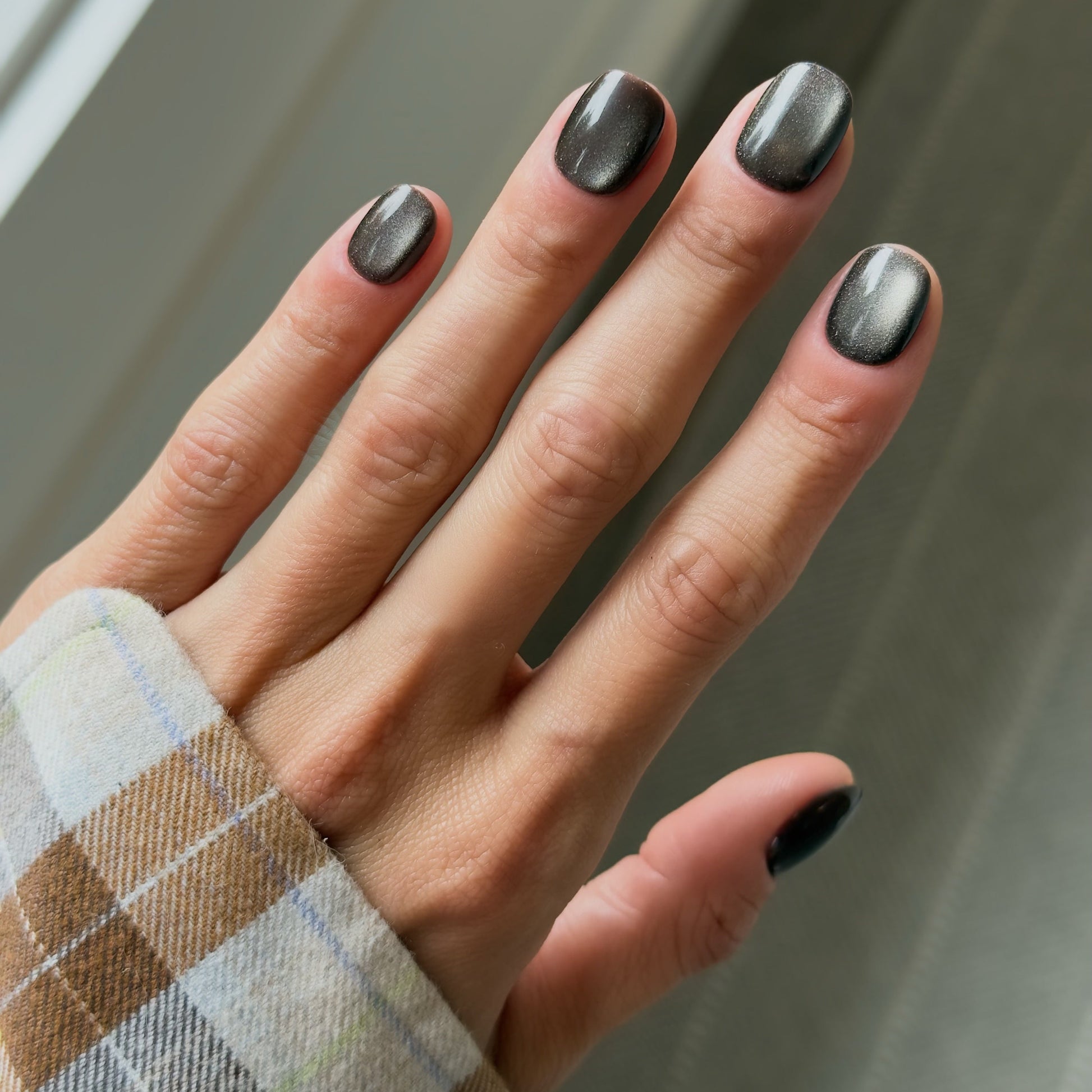 Hand with dark nail polish on a neutral background
