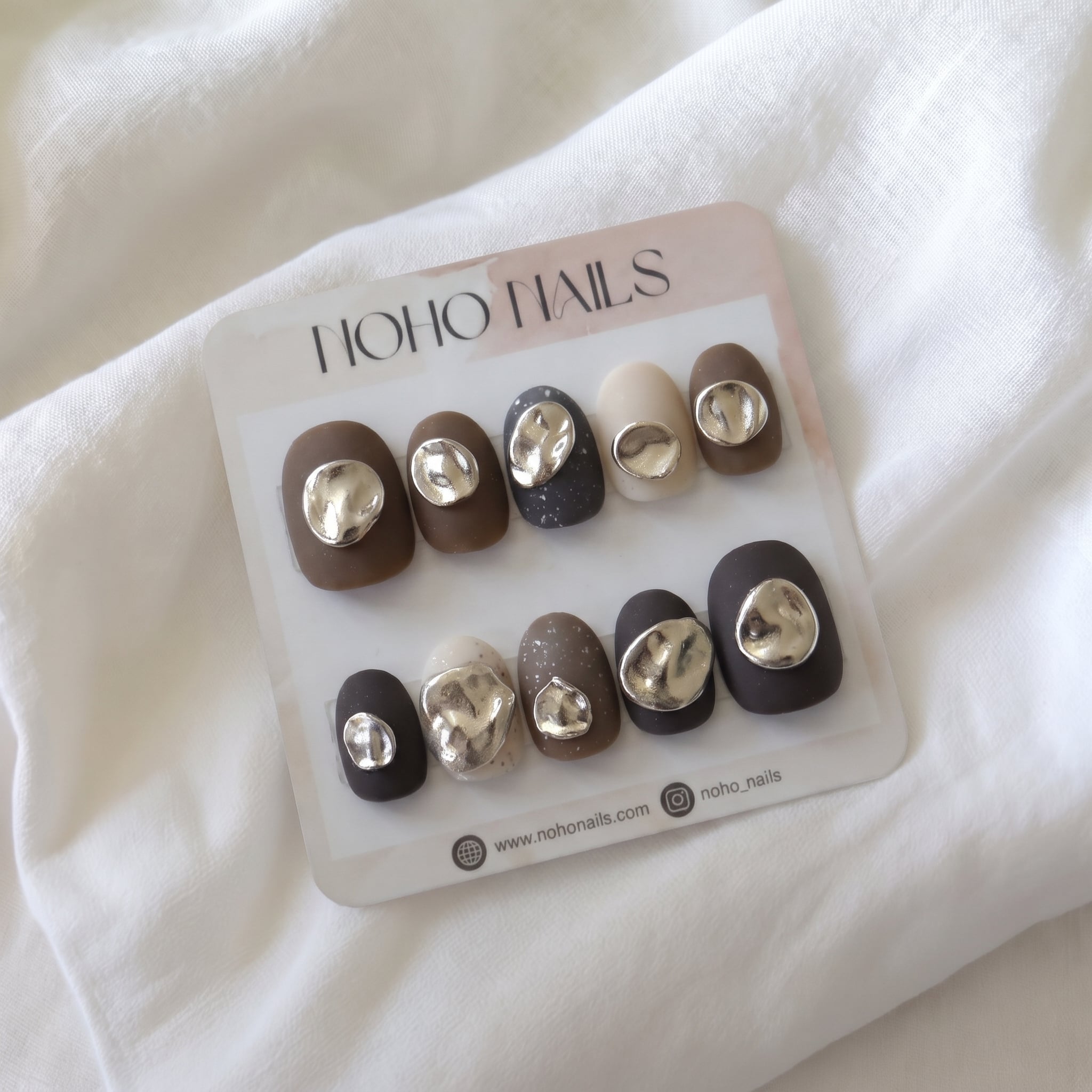 Iced Mocha press-on nails by Noho Nails: short matte brown, charcoal and cream nails with molten silver chrome accents on a Noho Nails display card