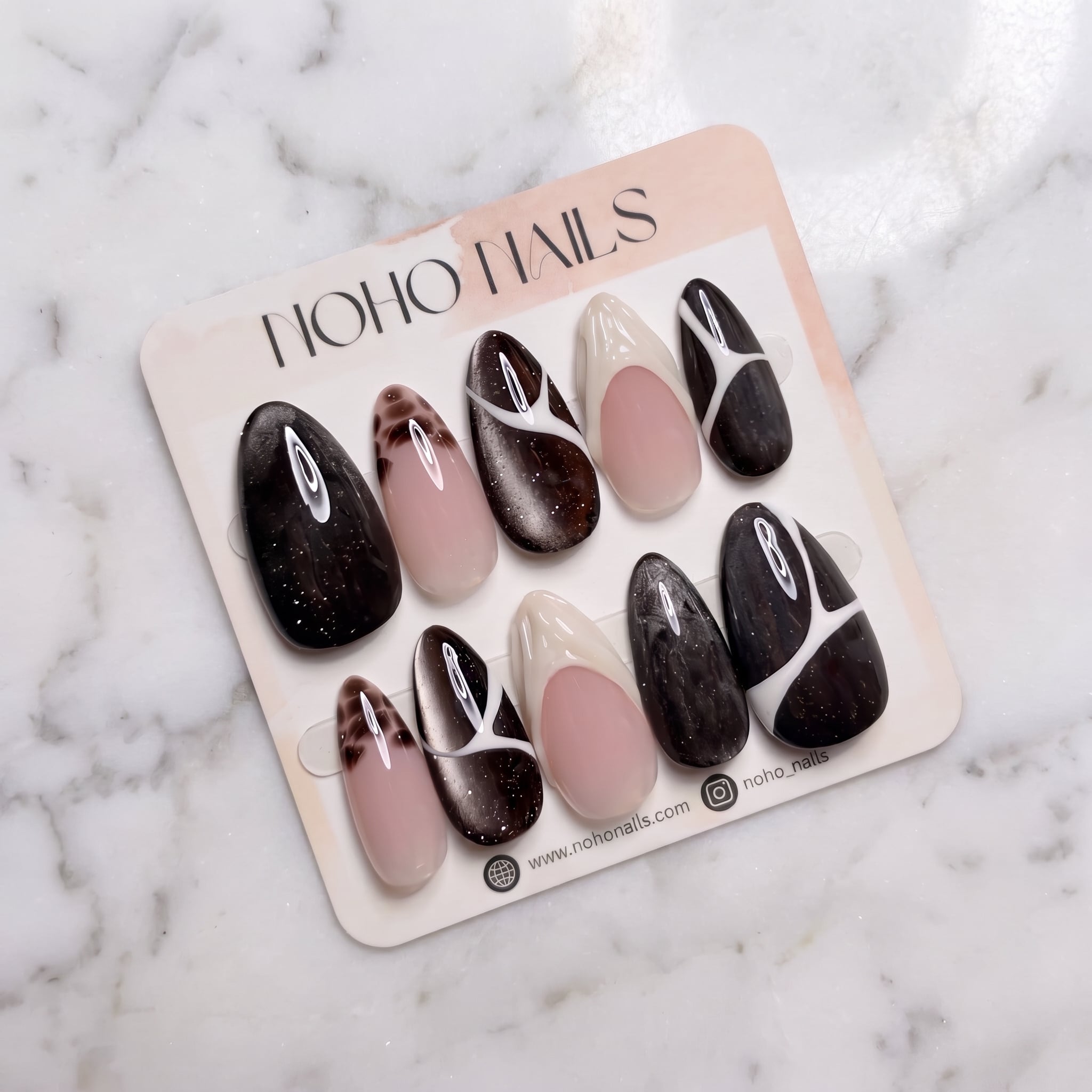 Café de Flore press-on nails on a Noho Nails display card lying on white marble