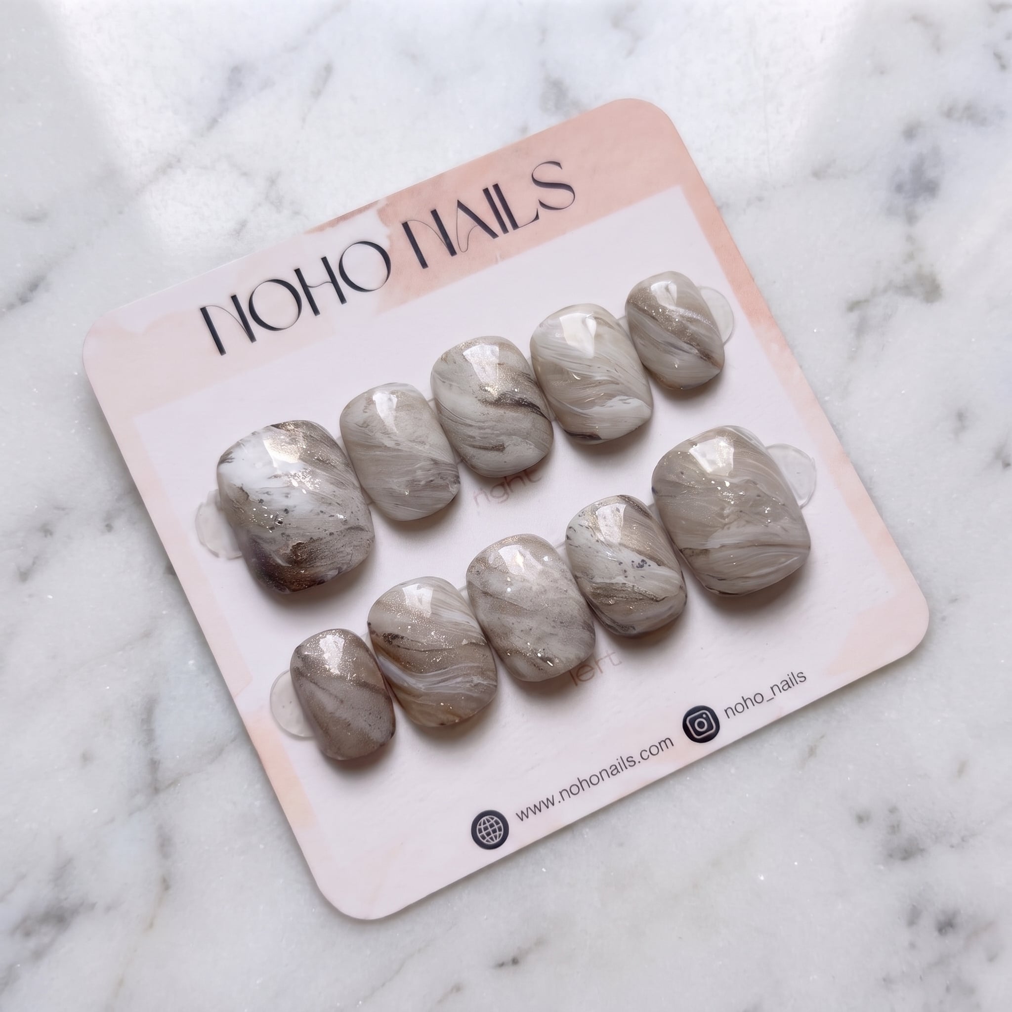 Sediment No. 9 press-on nails on a Noho Nails display card lying on white marble