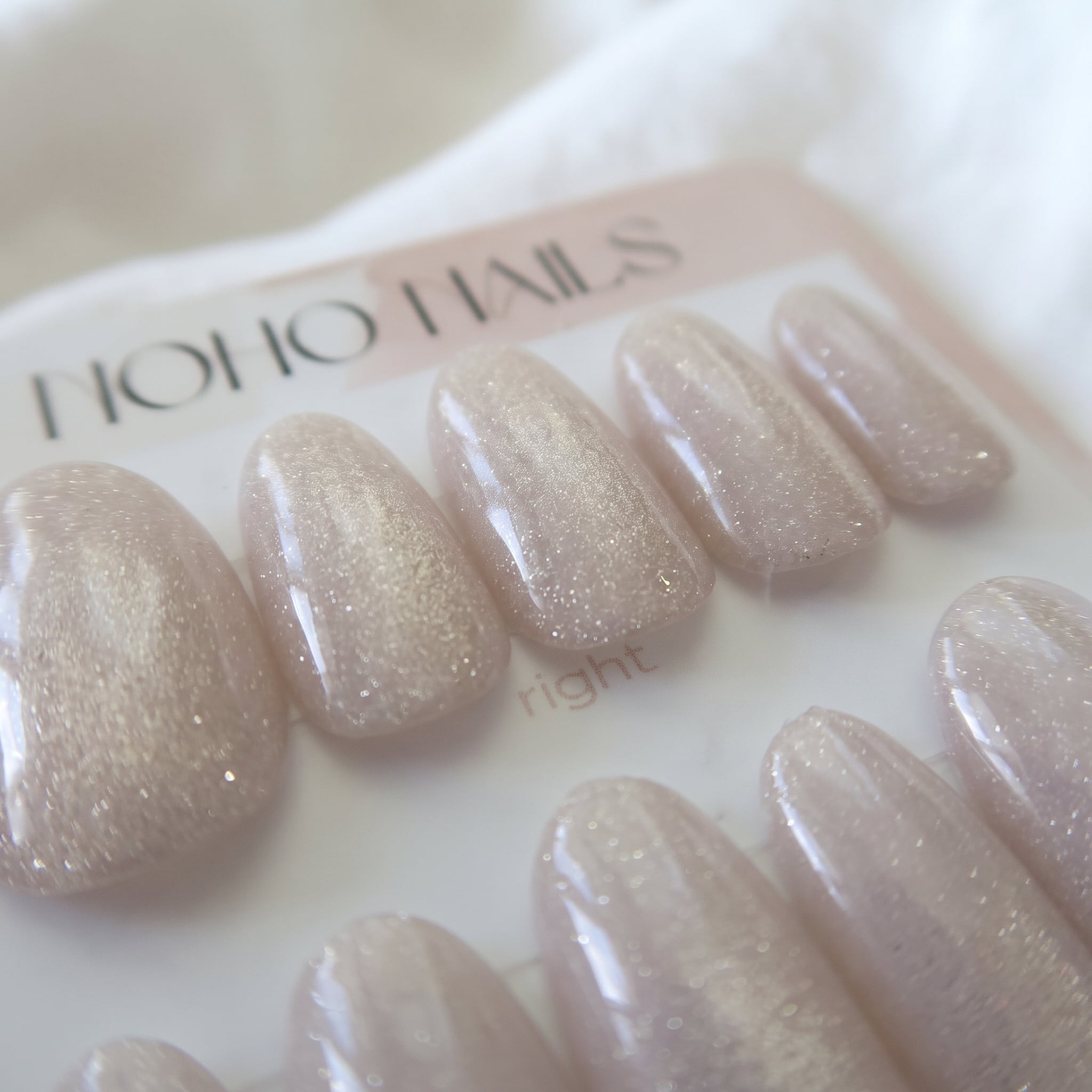 Close-up of Prosecco Pearl press-on nails by Noho Nails: milky blush-pink nails with champagne cat-eye shimmer