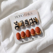 Out of Africa press-on nails by Noho Nails: cream nails with black abstract lines and terracotta nails with gold cuffs on a Noho Nails display card