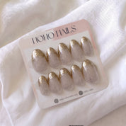 Golden Glaze press-on nails by Noho Nails: ten oval nails in sheer nude with speckled glitter and gold glitter tips on a Noho Nails display card