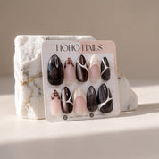 Café de Flore press-on nails on a Noho Nails display card propped against a white marble stone