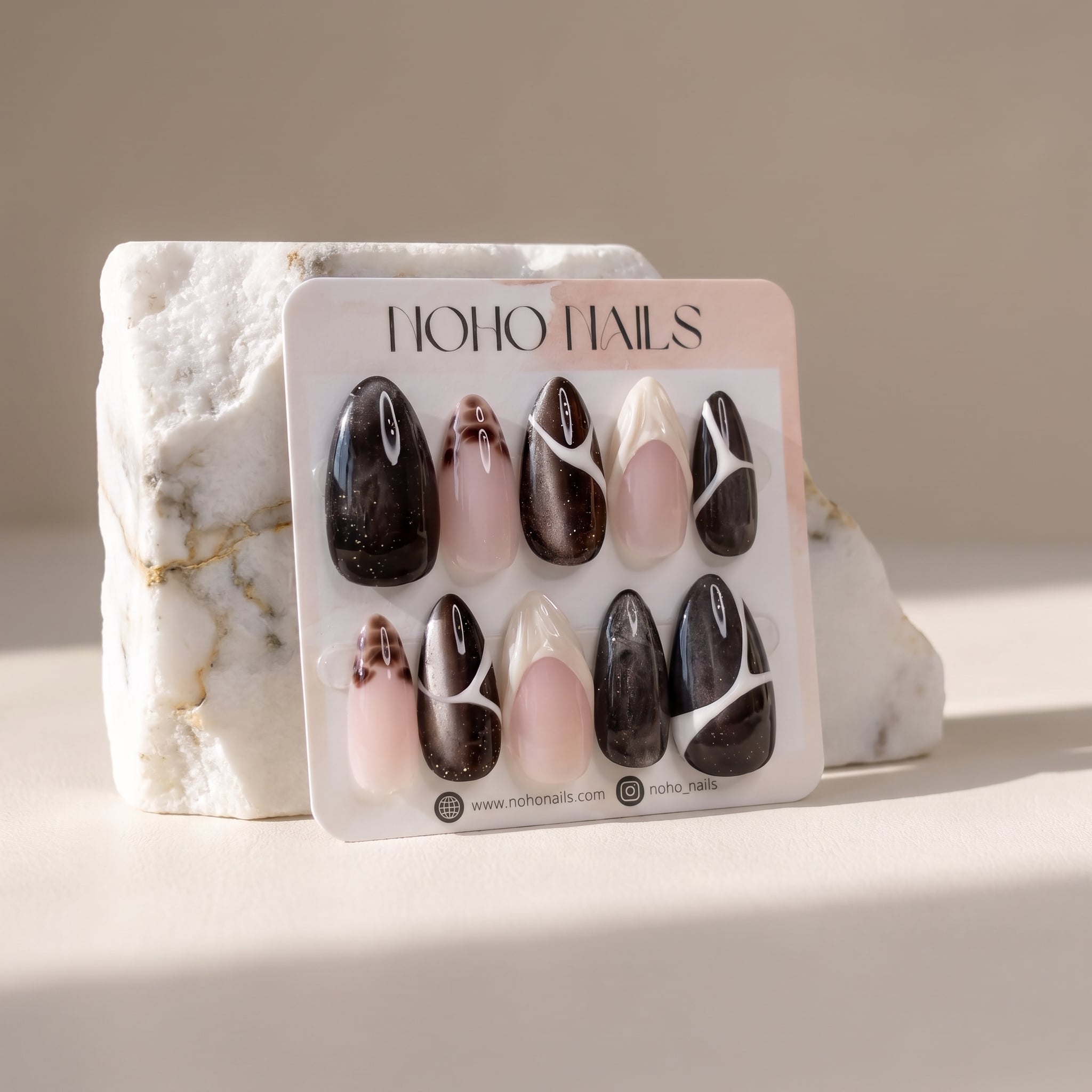 Café de Flore press-on nails on a Noho Nails display card propped against a white marble stone