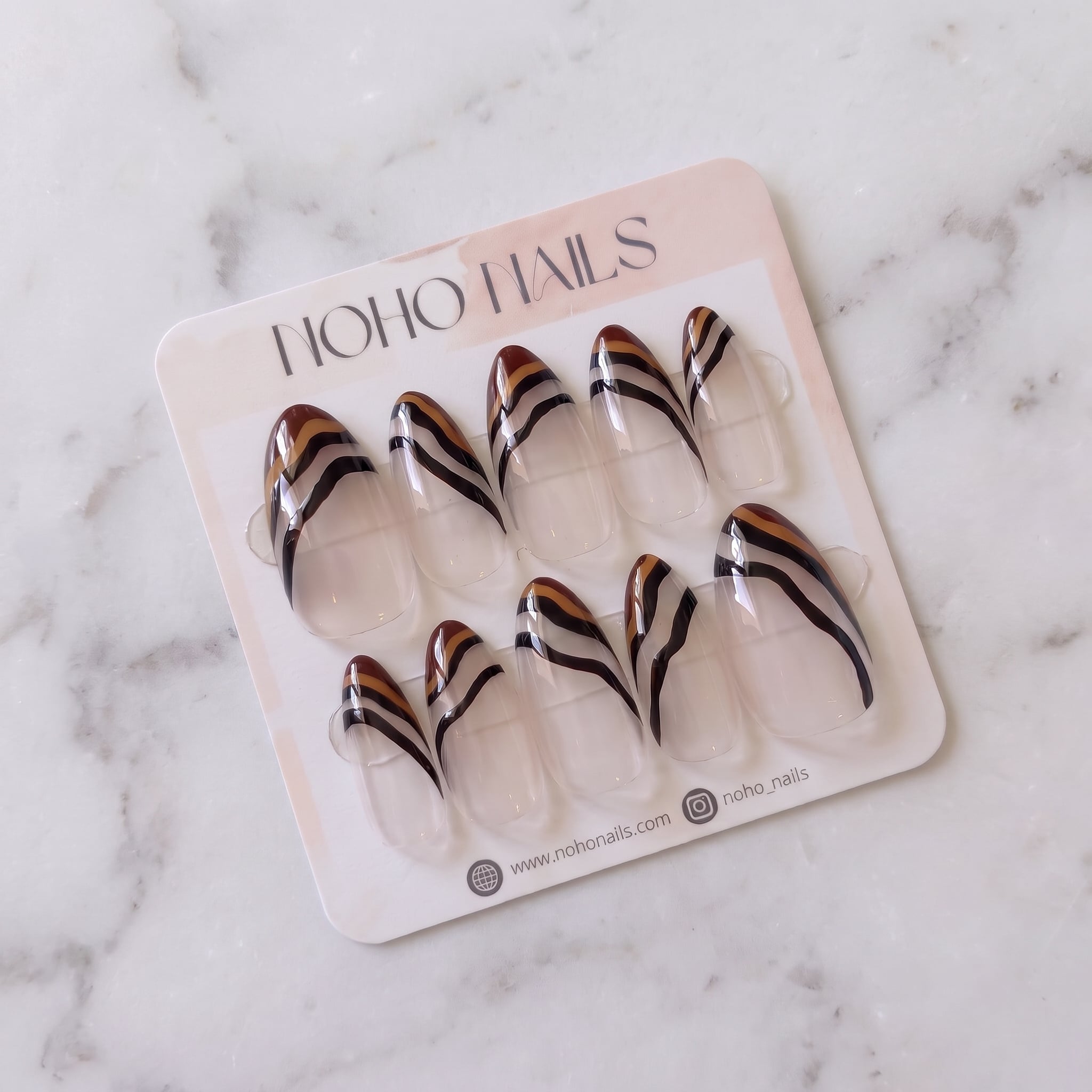 Ombre Portée press-on nails on a Noho Nails display card lying on white marble
